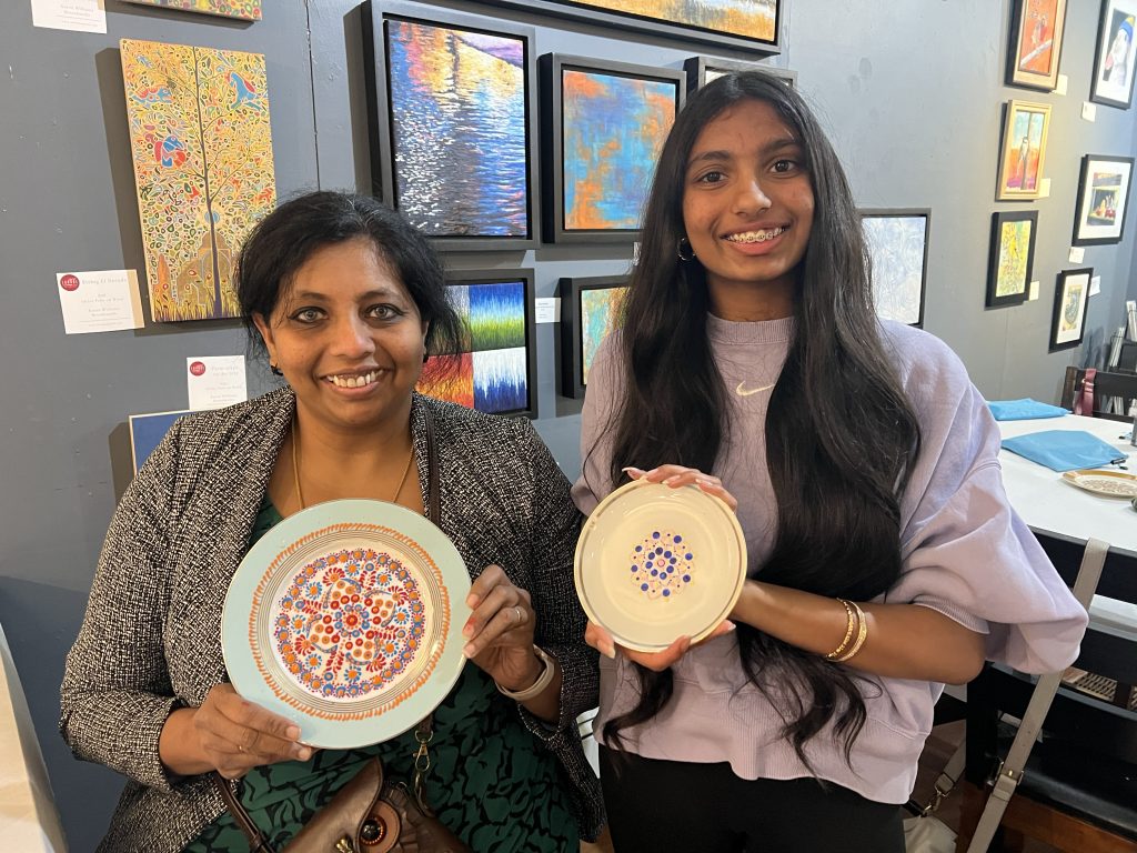 Photo of two ladies holding up their paint dotted plates from the Dotting Chick's 'sip and paint' at the Art Lounge in Menomonee Falls,